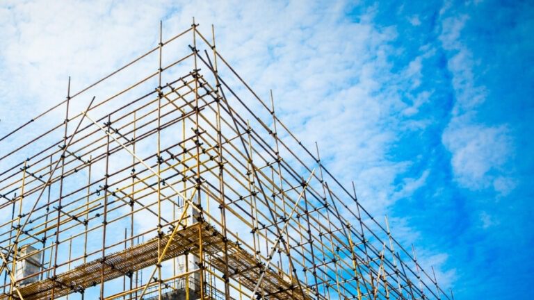 Scaffolding structure silhouetted against a vibrant sunset sky at a construction site.
